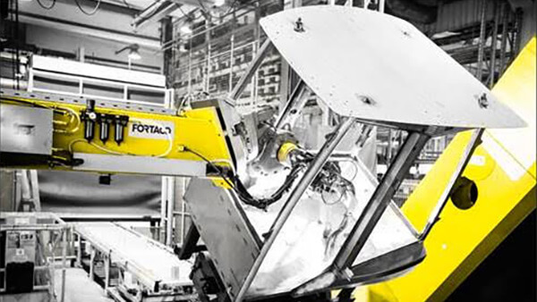 Yellow off-highway equipment assembly in a manufacturing plant
